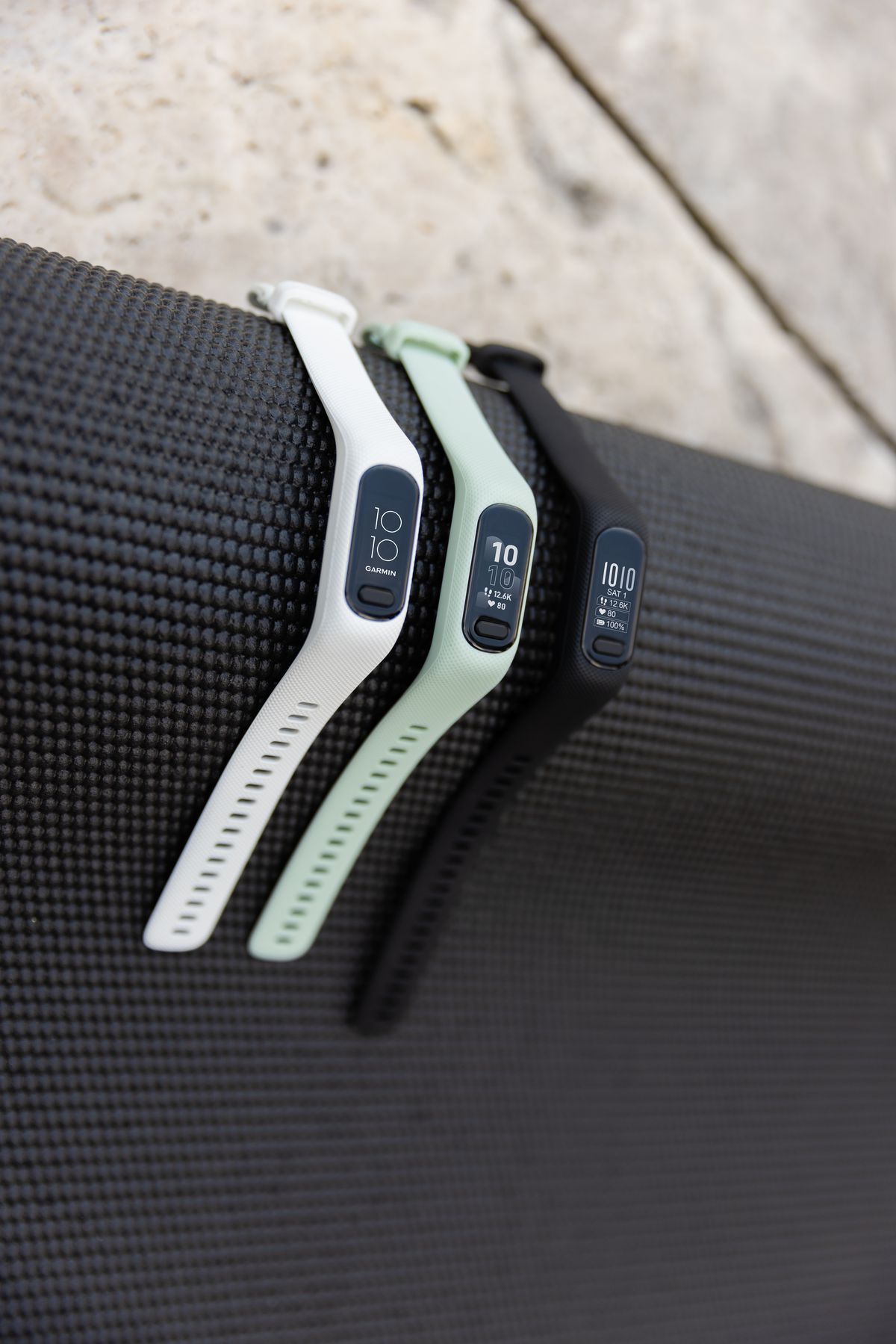 Garmin Vivosmart 5 in white, mint and black versions on black yoga mat